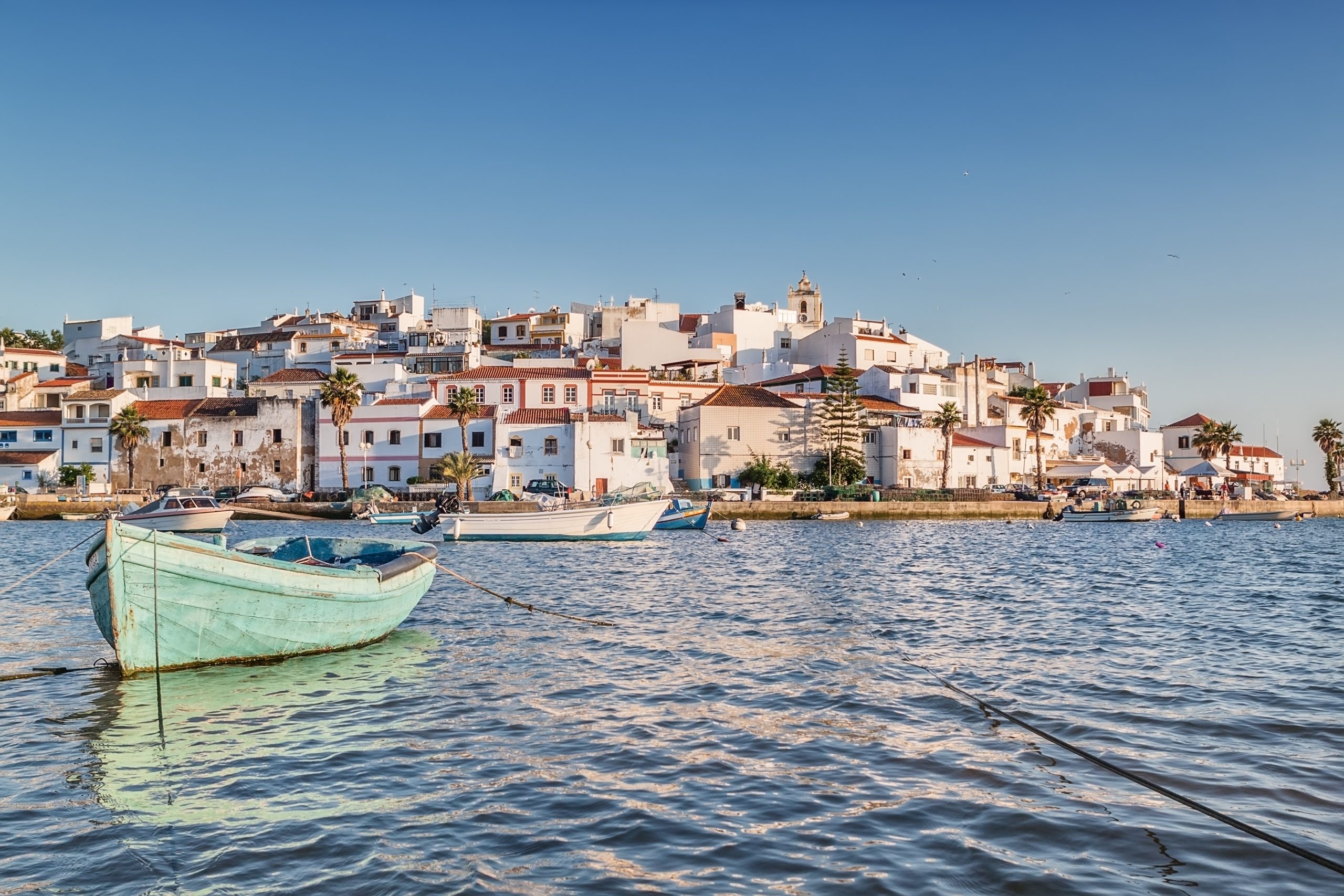 Ferragudo mit weißen Häusern und Fischerbooten an der Arademündung